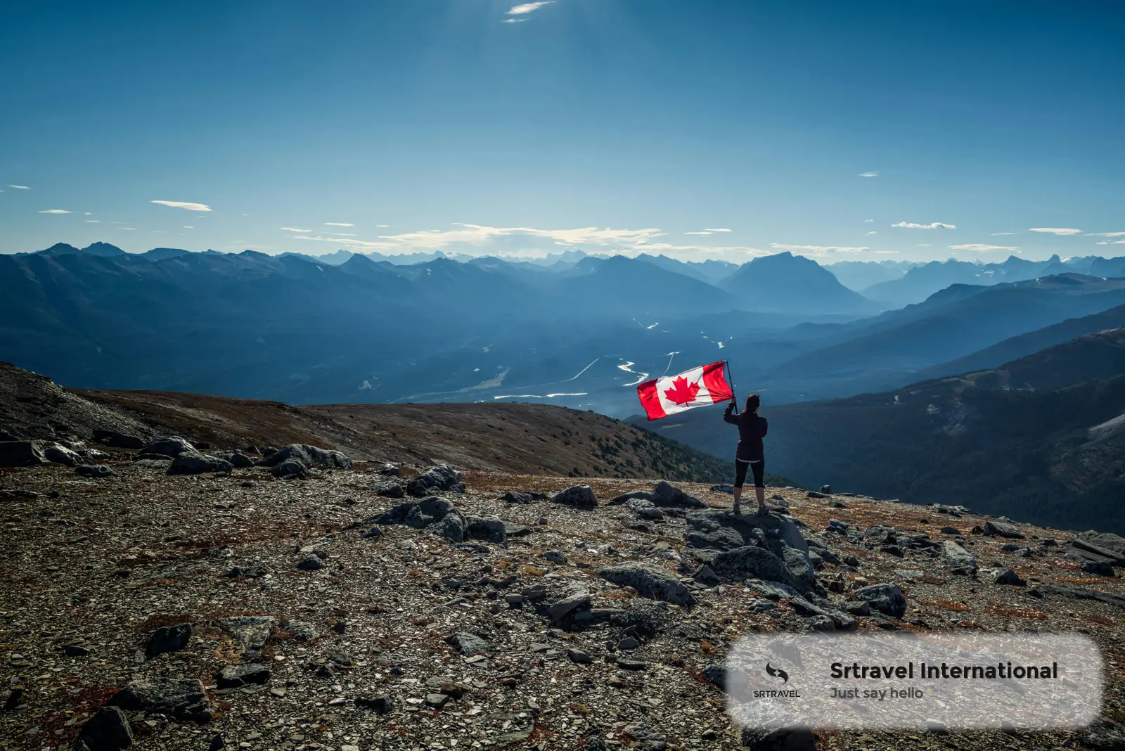 Khung cảnh núi hùng vĩ tại Canada với người cầm cờ Canada trên đỉnh núi