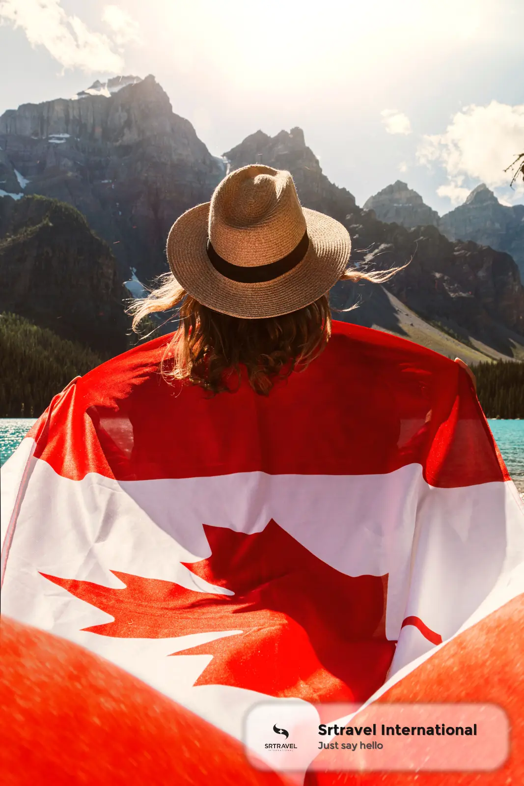 Người phụ nữ quàng cờ Canada nhìn ra núi tuyết trải dài trong chuyến đi du lịch Canada