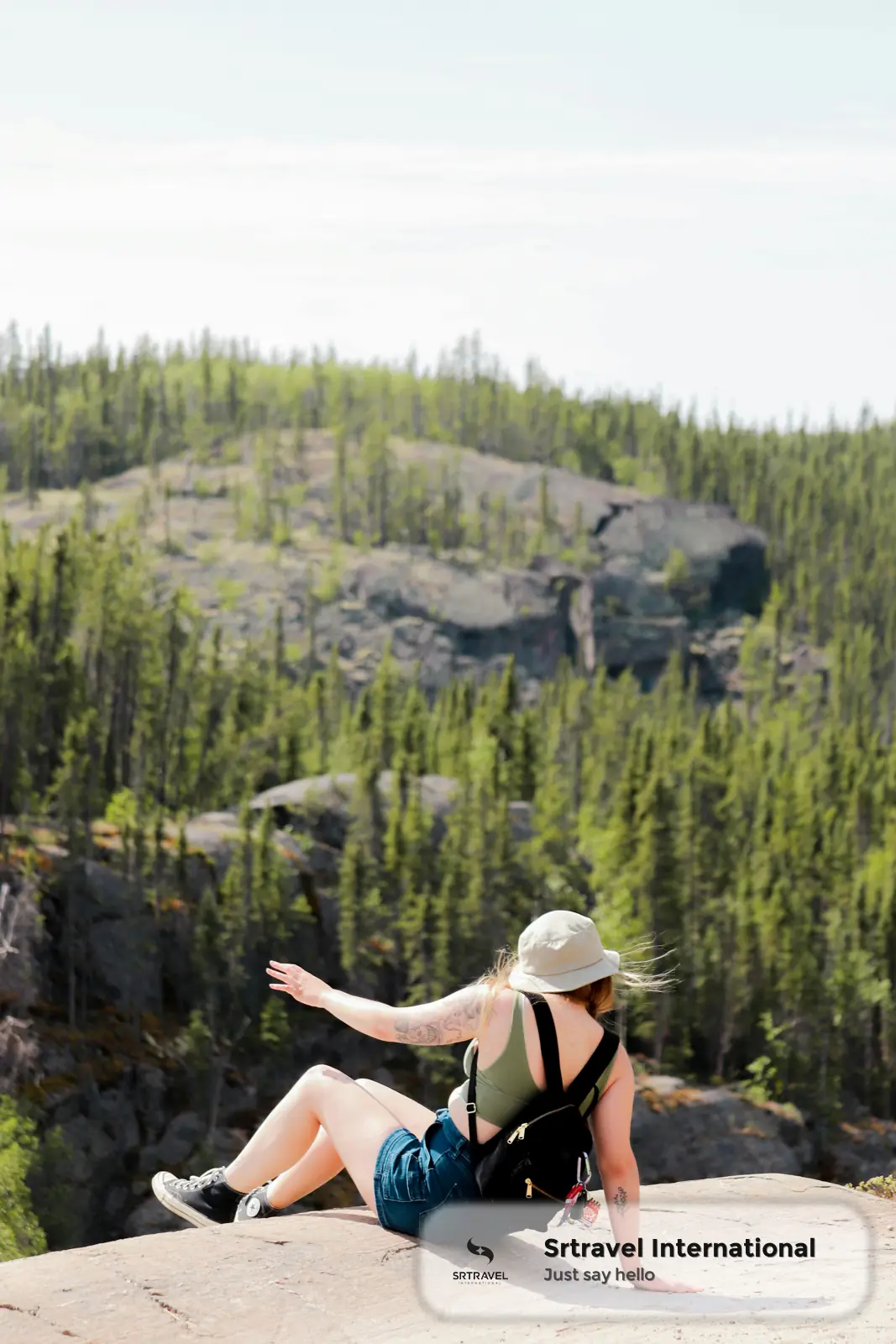 Du khách ngồi trên đá ngắm cảnh thiên nhiên rừng thông xanh mướt tại Canada
